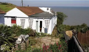  ??  ?? Bungalow on cliff edge before collapse. Left, the family car is left submerged