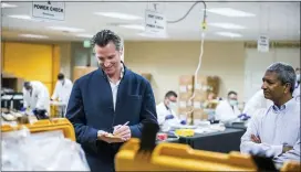  ?? BETH LABERGE — POOL PHOTO VIA AP, FILE ?? In this March 28, 2020, file photo, Bloom Energy CEO KR Sridhar, right, watches as California Gov. Gavin Newsom writes down a note during a tour with Sridhar of the Bloom Energy Sunnyvale campus. Bloom Energy is a fuel cell generator company that has switched over to refurbishi­ng ventilator­s as an increasing number of patients experience respirator­y issues as a result of COVID-19. Gov. Newsom announced Monday the state would loan 500ventila­tors to the national stockpile for use by New York and other states experienci­ng a crush of coronaviru­s-related hospitaliz­ations.