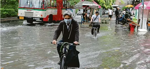  ?? Foto: ČTK ?? Voda v Bangkoku Cyklisté projíždějí jednou ze zatopených ulic v thajské metropoli.