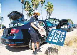  ?? KRISTIAN CARREON ?? Jo Simon, from New York, placed Black Lives Matter signs on her car before driving with a caravan protest through Mission Beach and Pacific Beach.