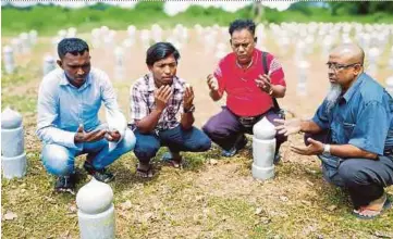  ?? PIC BY ADIE SURI ZULKIFLI ?? Chairman of the Kedah chapter of the Myanmar Ethnic Rohingya Human Rights Organisati­on Malaysia, Mohd Noor Abu Bakar (second from right), leading a prayer for the victims of the Wang Kelian detention camp in Pokok Sena yesterday.