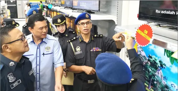  ??  ?? Md Nawawi (facing camera, right) points at a price tag while still in discussion with his KPDNKK-Customs enforcemen­t team during the operation on Giant Hypermarke­t Tabuan Jaya.