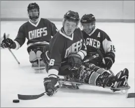  ?? Canadian Press photo ?? Humboldt Broncos hockey player Ryan Straschnit­zki, middle, passes the puck away from Marty Richardson, right, as Broncos teammate Jacob Wassermann follows the play during a sledge hockey scrimmage at the Edge Ice Arena in Littleton, Colo., on Friday. Both players were paralyzed from the waist down in the team's bus crash in April.