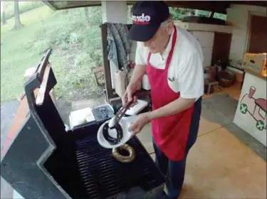  ?? JONATHAN TRESSLER — THE NEWS-HERALD ?? Bill Azman, whose Azman’s Quality Meats shop in Euclid claimed the 2018 Sausage Fest People’s Choice Award, plucks some of his award-winning fare off the grill during the 15th annual Slovenian Sausage Festival in Kirtland Sept. 12.