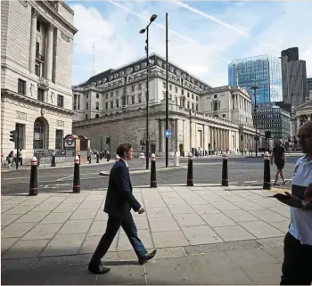  ?? — Bloomberg ?? Balancing act: City workers are seen passing the BOE building in London. The central bank has made it clear that it intends to retain a sizeable bond portfolio.