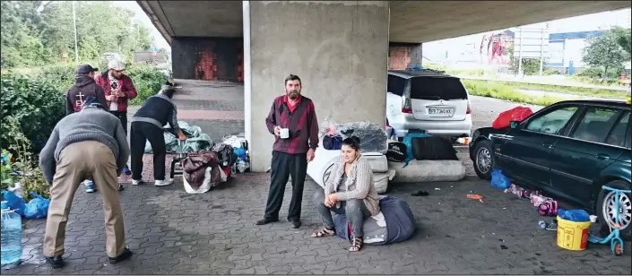  ??  ?? Home away from home: Migrants at their camp under the North Circular road in East London, where they sleep in the open or in their cars and beg for work during the day