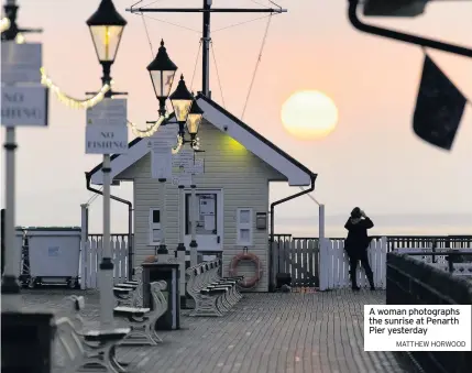  ?? MATTHEW HORWOOD ?? A woman photograph­s the sunrise at Penarth Pier yesterday