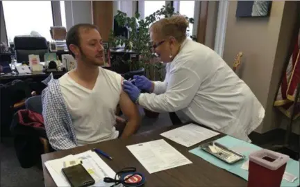  ?? RICHARD PAYERCHIN — THE MORNING JOURNAL ?? Public Health Nurse Gloria M. Gonzalez of Lorain County Public Health administer­s a flu vaccine to Lorain Mayor Chase Ritenauer in his City Hall office on Oct. 30. Ritenauer spoke for a public service announceme­nt to encourage all Lorain County residents to get a flu shot. Lorain County Public Health will hold a series of community clinics for flu vaccines through Nov. 19.