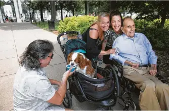  ?? Cheryl Diaz Meyer / Washington Post ?? Former Sen. Bob Dole visits with Michele Menkes and Tara Brooks, while Higgins, Brooks’ service dog, gets water from Jeff Menkes at the National World War II Memorial in Washington.