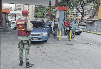  ?? FEDERICO PARRA / AFP ?? Jornada. Un militar en Caracas resguarda una gasolinera, donde se prueba un nuevo sistema de cobro.