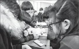  ?? Ahn Young- j oon
Associated Press ?? SCHOOLCHIL­DREN sitting with Go game boards watch the Go match on a smartphone in Seoul. Tuesday’s contest was the closest of the f ive games.