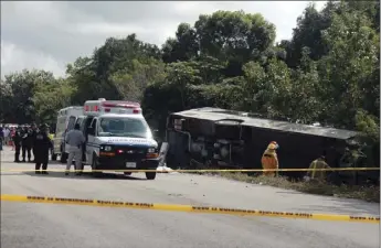  ??  ?? An ambulance sits parked next to an overturned bus in Mahahual, Quintana Roo state, Mexico, on Tuesday. The bus carrying cruise ship passengers to the Mayan ruins at Chacchoben in eastern Mexico flipped over on a highway early Tuesday. AP PHOTO