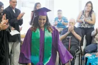  ?? LUIS SÁNCHEZ SATURNO/THE NEW MEXICAN ?? Lexus Romero of Engage Santa Fe, the first to wear the new robe for her school, prepares to receive her diploma Wednesday during the summer graduation ceremony for 21 public school students.