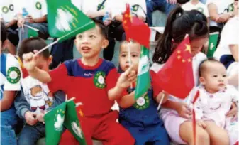  ??  ?? October 31, 1999: Macao children wave the national flag of China and the flag of the Macao SAR in the streets to celebrate the 50-day countdown to Macao's return to the motherland. by Mao Jianjun/cns