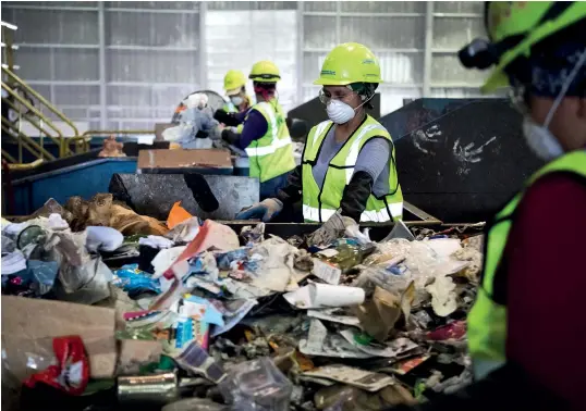  ?? Photos: VCG ?? Counterclo­ckwise from left: A worker is moving bales of recycled materials at a recycling facility run by Waste Management in Elkridge, Maryland. Workers go through recyclable­s by hand to remove items seen as “contaminan­ts.” Piles of compacted plastics and paper Trash is piled up at the Fort Totten Transfer Station in Washington. About 900 tons of trash are dumped at all hours of the day and night, five days a week, on the conveyor belts.
