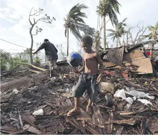  ??  DAVE HUNT/GETTY IMAGES FILES ?? Samuel walks through the ruins of his family home with his father Phillip on Monday in the Vanuatu capital of Port Vila. Cyclone Pam hit South Pacific islands on Saturday.