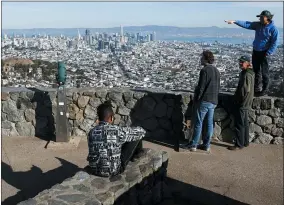  ?? JESSICA CHRISTIAN/SAN FRANCISCO CHRONICLE VIA AP ?? Tourists look out onto the city skyline from Christmas Tree Point on top of Twin Peaks in San Francisco, Thursday, Dec. 15, 2022.