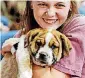  ??  ?? Senior Laura Hoehner holds one of two puppies sold during the live auction portion of the final Swine Week assembly, culminatin­g a weeklong effort to raise funds to benefit selected nonprofit groups.