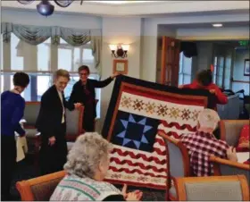  ??  ?? Attendees applaud as Nancy McCormack and Joanne Gressang display the Quilt of Valor presented to World War II Marine Grace Bergman, the oldest living female Marine in Pennsylvan­ia.