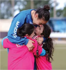  ??  ?? Fun Coaching! Two young girls happily cling to their female football coach during the “Live Your Goals Festival”. Photo: Domenic Aquilina