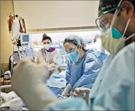  ?? FRANCINE ORR Los Angeles Times ?? NURSE LIA CHRISTIAN, middle, and Dr. Babak Eshagian, right, work with a patient at Providence Holy Cross Medical Center in Los Angeles on Dec. 9.