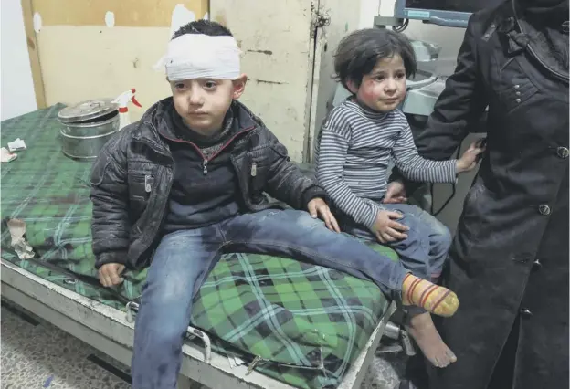  ??  ?? 0 A bandaged Syrian child sits on a bed next to another child after receiving medical attention at a makeshift hospital in the rebel-held town of Douma, in the besieged Eastern Ghouta region outside the cap ital, Damascus, where government forces launched a large scale offensive last month.