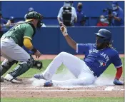  ?? JON BLACKER — THE CANADIAN PRESS ?? The Toronto Blue Jays’ Vladimir Guerrero Jr., right, slides safely into home ahead of a tag by Oakland Athletics catcher Yan Gomes (19) in the fourth inning Sunday in Toronto.