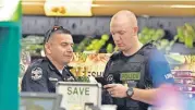  ?? [AP PHOTO] ?? Members of the Louisville Metro Police Department talk inside a Kroger grocery store in Jeffersont­own, Ky., following a shooting that left two people dead Wednesday.