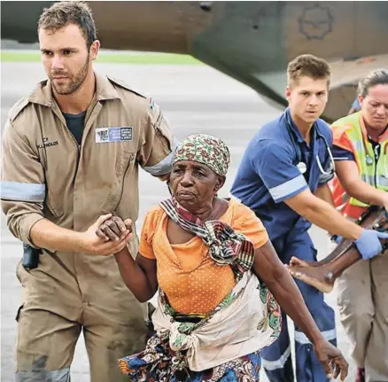  ?? Picture: ADRIEN ?? HELPING HAND: People are escorted to safety by aid workers at the airport of the coastal city of Beira in central Mozambique on March 19, 2019, after the area was hit by the Cyclone Idai. More than 80 people were rescued by Rescue South Africa and the South African army with helicopter­s from the Buzi area, province of Safala, where they were stranded since March 15. Rescue workers in Mozambique were racing against time to pluck people off trees and rooftops on March 19, after a monster storm reaped a feared harvest of more than 1,000 lives before smashing into Zimbabwe