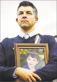  ?? Associated Press file photo ?? Ian Hockley, father of Sandy Hook School shooting victim Dylan, holds a picture of his son during a news conference in Newtown in 2013.