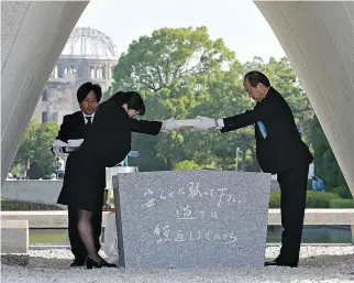  ?? AFP ?? HIROSHIMA Mayor Kazumi Matsui (right) offers a new list of A-bomb dead, including individual­s who died since last year’s anniversar­y from the side effects of radiation, during the 73rd anniversar­y memorial service for the atomic bomb victims at the Peace Memorial Park in Hiroshima on Aug. 6. A bell tolled that day in Hiroshima as Japan marked 73 years since the world’s first atomic bombing, with the city’s mayor making a passionate plea for a world without nuclear weapons.