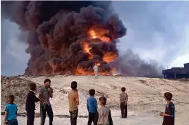  ?? THE ASSOCIATED PRESS ?? People watch a burning oil well Sunday in Qayyarah, about 31 miles south of Mosul, Iraq. Islamic State fighters torched a sulfur plant, sending a cloud of toxic fumes into the air that mingled with oil wells the militants had lit on fire to create a...