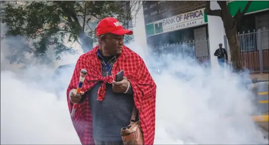  ?? ?? Pasha is surrounded Friday by tear gas thrown by police to break up a demonstrat­ion.