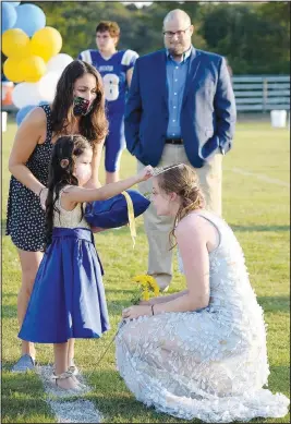  ??  ?? With her father Jeremy looking on (background), queen Anabelle Schopper (right) receives her crown from Kendra Regalado during the homecoming coronation ceremony at Bulldog Stadium.
(NWA Democrat-Gazette/Mike Eckels)