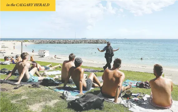  ?? PAUL KANE/GETTY IMAGES ?? Police in Perth, Australia, encourage beachgoers to increase their space on Thursday, as authoritie­s worldwide struggle to bring home the message of social distancing.