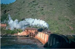  ?? ?? The famous curving Kaaimans River Bridge is crossed with the morning mixed train behind Class 24 2-8-4 No. 3027 from George to Knysna on October 4,1978. Above the rear carriages, the land has since slipped, engulfing the line.