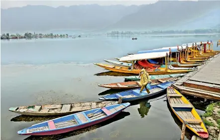  ?? — PTI ?? A woman at the deserted Dal Lake after the government announced a lockdown following a massive increase in the death toll due to the Coronaviru­s, in Srinagar on Tuesday.