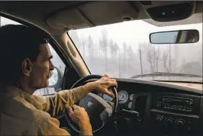  ??  ?? DRIVING HIS pickup truck through town last week, Evans heads to check on a list of properties sent to him by neighbors still unable to return because of evacuation orders.