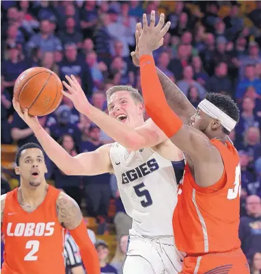  ?? ELI LUCERO/ASSOCIATED PRESS ?? New Mexico’s Carlton Bragg, right, attempts to block the shot of Utah State’s Sam Merrill (5) during their game Wednesday in Logan, Utah. The Lobos lost and dropped into ninth place in the MWC.