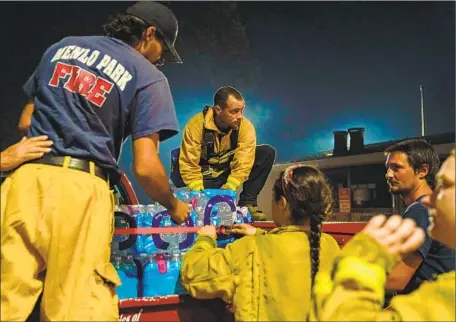  ?? Photograph­s by Kent Nishimura Los Angeles Times ?? SUPPLIES from Menlo Park are unloaded at the Boulder Creek Volunteer Fire Department amid the CZU Lightning Complex fire.