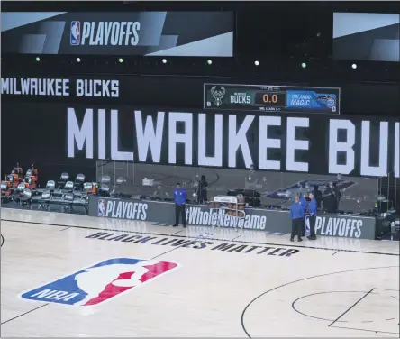  ?? ASHLEY LANDIS ?? Officials stand beside an empty court at the scheduled start of an NBA basketball first round playoff game between the Milwaukee Bucks and the Orlando Magic, Wednesday, Aug. 26, 2020, in Lake Buena Vista, Fla. The Milwaukee Bucks didn’t take the floor in protest against racial injustice and the shooting of Jacob Blake, a Black man, by police in Kenosha, Wisconsin.