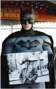  ?? Foto: dpa ?? Ein als Batman verkleidet­er Mann hält ein Foto des Comic-Zeichners Bob Kane in den Händen, der von 1915 bis 1998 lebte. Vor 80 Jahren erfand der Mann auf dem Foto den berühmten „Fledermaus­Mann“.