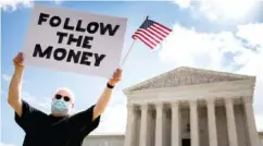  ?? AP PHOTO/ANDREW HARNIK ?? Bill Christeson holds up a sign that reads “Follow the Money” outside the Supreme Court on Thursday in Washington.