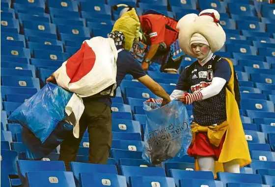  ?? —AFP ?? RUBBISH-TREE Supporters of Japan’s football team collect rubbish at Rostov Arena in Rostov-On-Don, Russia, after it lost to Belgium in the last-16 stage.