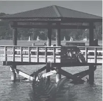  ?? STAFF FILE PHOTO BY TIM BARBER ?? People relax on one of the fishing piers at Booker T. Washington State Park in 2016 as the weekly sailboat race from Privateer Yacht Club gets underway on Chickamaug­a Lake.