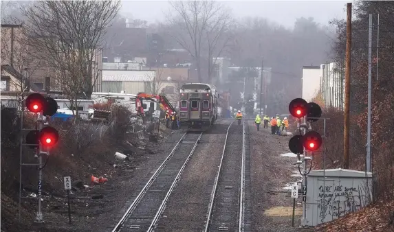  ?? FAITH NINIVAGGI PHOTOS/ HERALD STAFF ?? IDEA TRAIN: A disabled MBTA commuter train, above, sits on the tracks Tuesday. Workers, below, secure chains from a crane to lift the disabled train Tuesday after it derailed in Belmont.