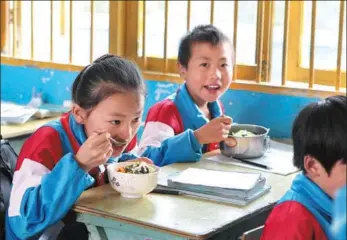  ?? PROVIDED TO CHINA DAILY ?? Primary school students in Songyao County in Guizhou province in Southwest China tuck into a meal provided by the China Developmen­t Research Foundation.