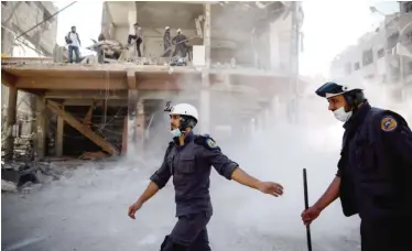  ??  ?? Syrian civil defense volunteers, known as White Helmets, work around destroyed buildings following reported air strikes on the rebel-held town of Douma on the eastern outskirts of the capital Damascus on Oct 5, 2016. — AFP