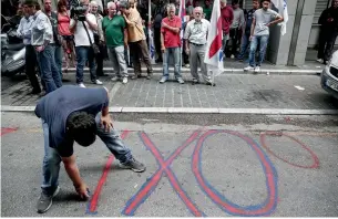  ?? — AP ?? A supporter of the Greek Communist Party paints the word ‘No’ on a street during an anti-austerity rally outside the Finance Ministry in Athens on Thursday.