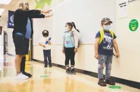  ?? Jessica Christian / The Chronicle ?? At Oakland’s Garfield Elementary School, teacher Michele Witherspoo­n shows her firstgrade­rs how to use their arms to gauge social distance in April.